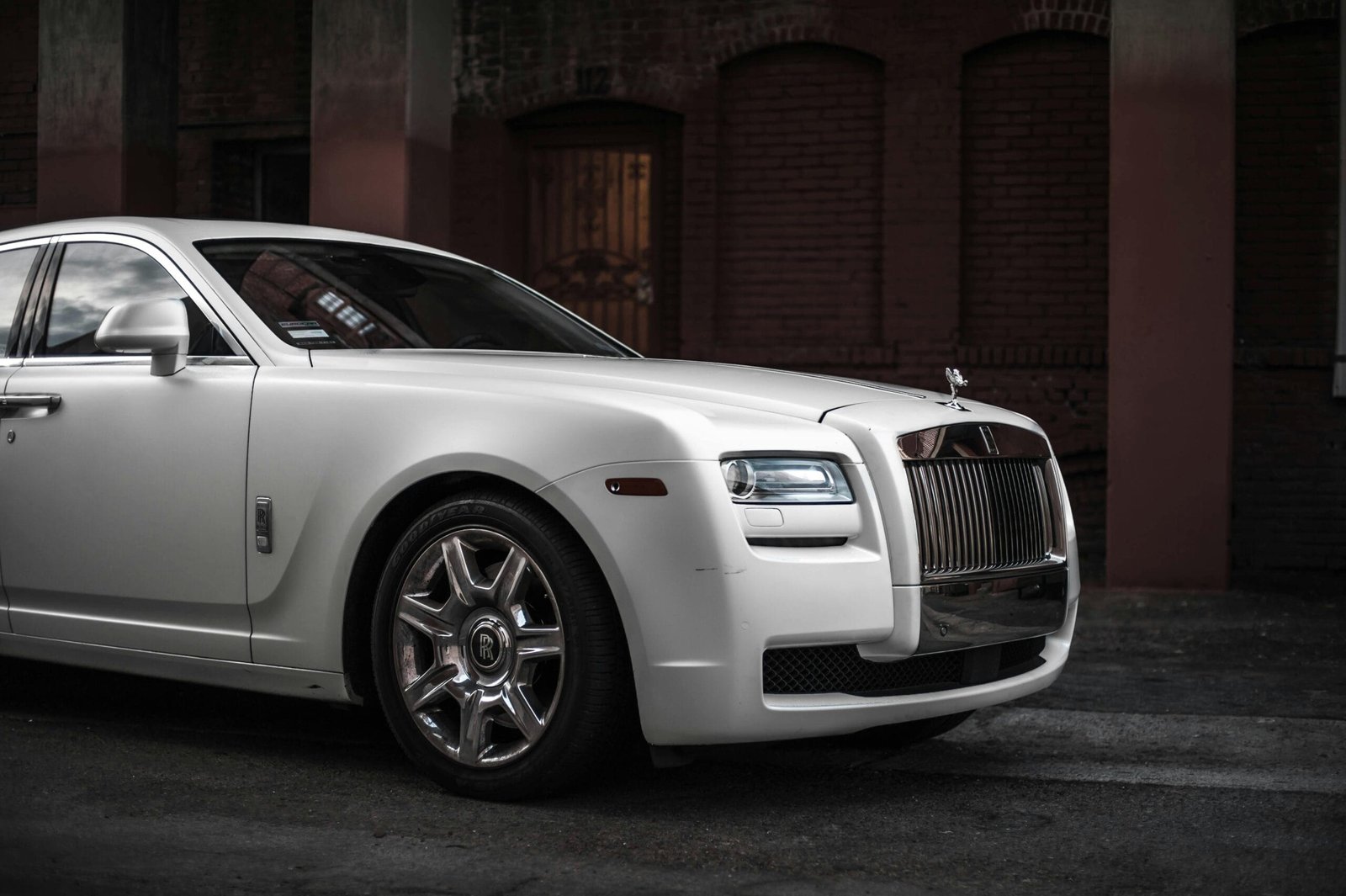 Madge Mansions 1 Elegant white Rolls Royce Ghost parked in a stylish urban backdrop, showcasing luxury and design.